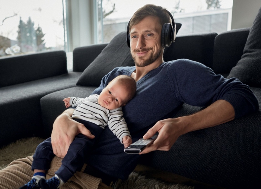 Man watching TV and wearing Philips TAH9505 headphones